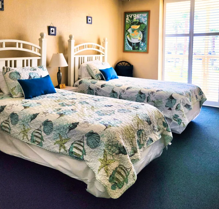 A coastal guest room with patterned bedding and natural light