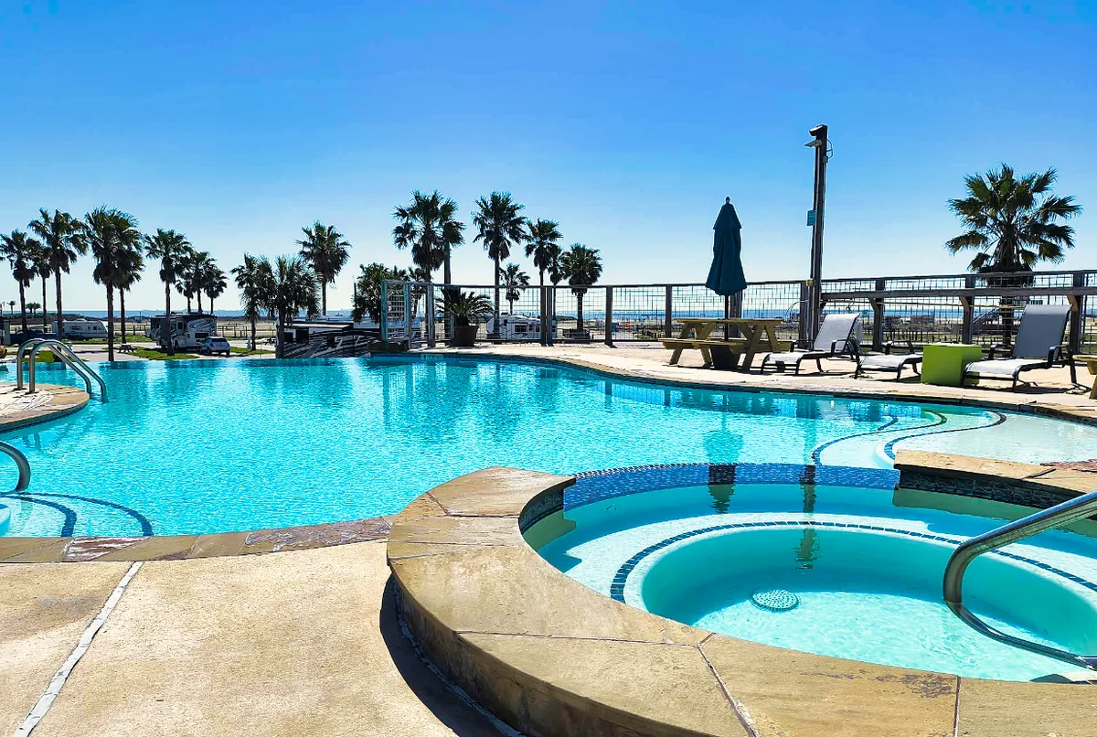 Sandpiper’s Gulf-facing pool and hot tub, with palms and RV sites beyond the deck